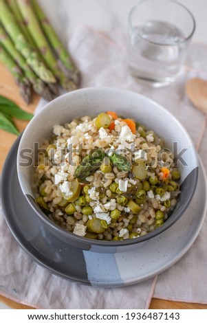 healthy barley soup with spring vegetables, asparagus, wild garlic and carrots