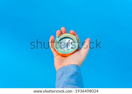 The child holds in his hand a compass against a blue background.