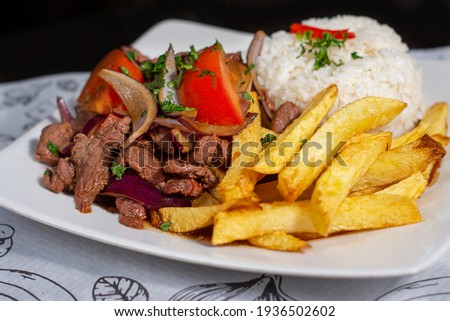 Peruvian traditional food. A beef with tomatoes, onion, rice and fried potatoes, Lomo saltado. Royalty-Free Stock Photo #1936502602