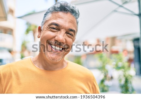 Middle age grey-haired man smiling happy walking at street of city.