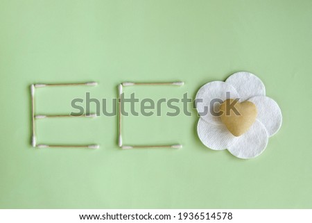ECO - word made from BIOdegradable hygiene cotton buds and cotton pads on green background. Top view. Copy space. Selective focus.
