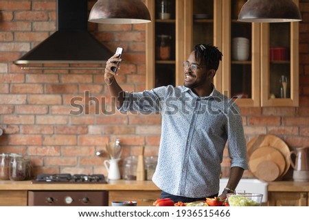 My culinary feats. Overjoyed afro caribbean male hipster shoot selfie on phone at home kitchen to share at social networks. Joyful young black male posing for self picture at moment of cooking food