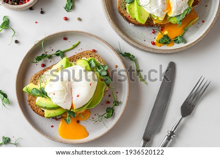 Healthy breakfast. Whole wheat toasted bread with avocado, poached egg, soft cheese and sprouts on white background. top view. Healthy diet food Royalty-Free Stock Photo #1936520122