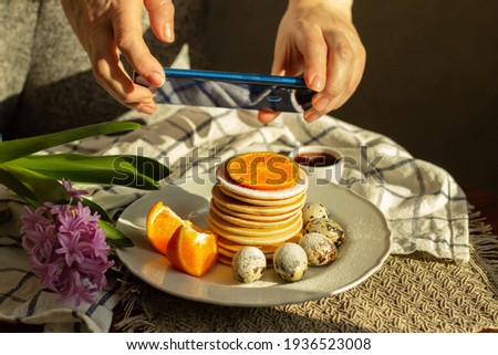 Girl woman takes pictures on her cell phone of a pancake breakfast dessert that she made herself
