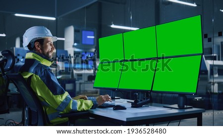 Industry 4.0 Modern Factory: Facility Operator Controls Workshop Production Line, Uses Computer with 6 Displays Showing Green Screens Chroma Key Mock up Template. Controls Machine Operation Processes.