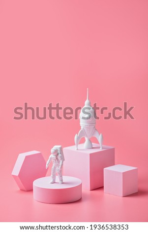 Astronaut figurine on the podium on a pink background. International Day of Human Space Flight concept