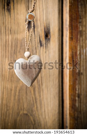Heart hanging on nails, wooden texture background. Studio photo.