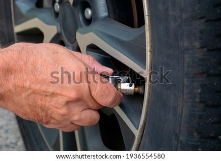 Man calibrating car tire - closeup on hand Royalty-Free Stock Photo #1936554580