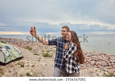 Young couple hiking taking selfie with smart phone. Happy young man and woman taking self portrait with mountain scenery in background.