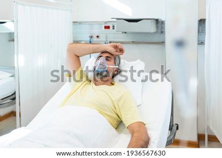 Portrait of retired senior man breathing slowly with oxygen mask during coronavirus covid-19 outbreak. Old sick man lying in hospital bed, getting treatment for deadly infection