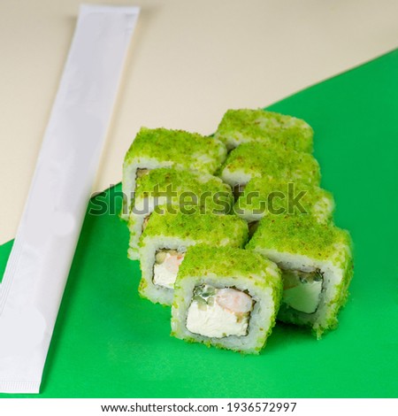 Sushi with green caviar and cream cheese on a green background. Close-up