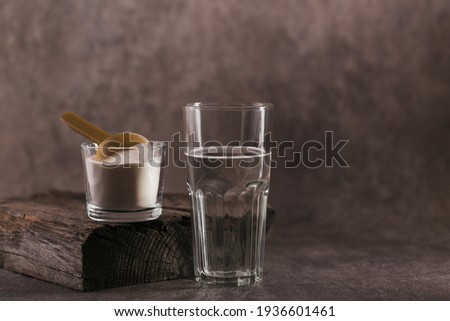 Glass with collagen dissolved in water and collagen protein powder on brown background. Healthy lifestyle concept.