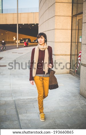 young beautiful hipster woman listening music with headphones in the city
