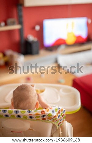 Baby girl watching cartoons on TV and eating balanced meal