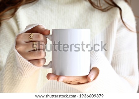 Girl in white sweater holding white coffee mug  , white porcelain mug mock up  Royalty-Free Stock Photo #1936609879