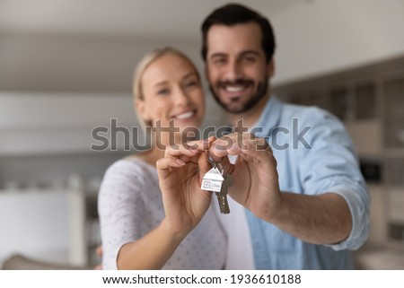 Close up focus of happy young Caucasian couple show keys to first share own apartment or house. Smiling millennial man and woman celebrate relocation to new home. Moving, rental, estate concept. Royalty-Free Stock Photo #1936610188