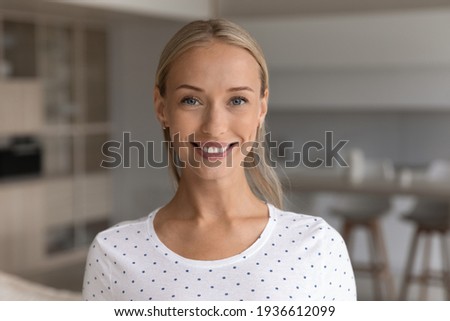 Headshot portrait of smiling young 20s Caucasian woman renter or tenant pose in living room in new home. Close up profile picture of happy millennial female in own house. Rental, employment concept.