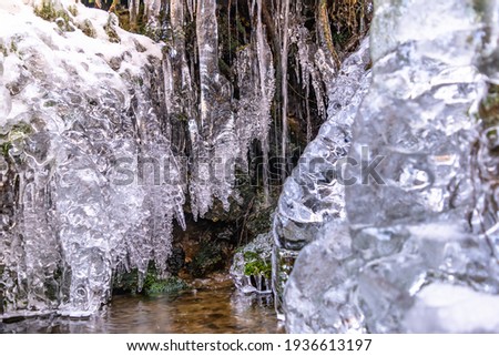 Waterfall in winter. Water jets freeze and icicles form. Attractive ice shapes and white frost - like a theater stage and impressive winter sets.