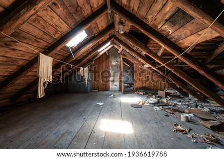 Attic room with clothesline, wooden trim and junk on the floor Royalty-Free Stock Photo #1936619788