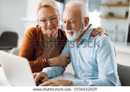 Happy  mature couple using  laptop at home Royalty-Free Stock Photo #1936622029