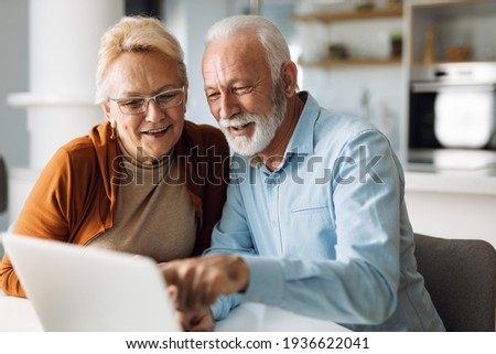 Happy  mature couple using  laptop at home Royalty-Free Stock Photo #1936622041