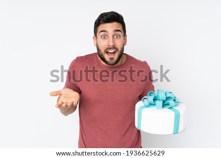 Pastry chef with a big cake isolated on white background with shocked facial expression