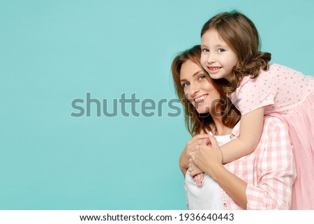Happy woman in pink clothes have fun with cute child baby girl 5-6 years old Mommy little kid daughter stand behind hug isolated on pastel blue azure background studio Mother's Day love family concept