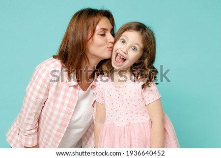 Happy woman in pink clothes have fun with cute child baby girl 5-6 years old. Mommy little kid daughter kiss on cheek isolated on pastel blue azure background studio. Mother's Day love family concept