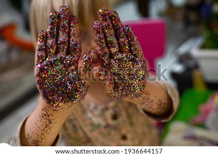 hands of a little girl, a child who plays with jars of sparkles. Child development, fine motor skills, hobbies, classes and home education.