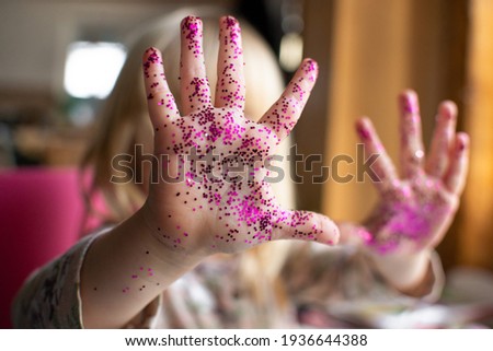 hands of a little girl, a child who plays with jars of sparkles. Child development, fine motor skills, hobbies, classes and home education.