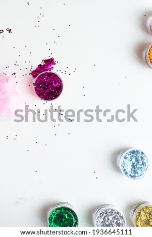 Jars of multicolored sparkles on a white table. Materials and goods for handicraft, decoration and decoration for the holiday. Development of children.