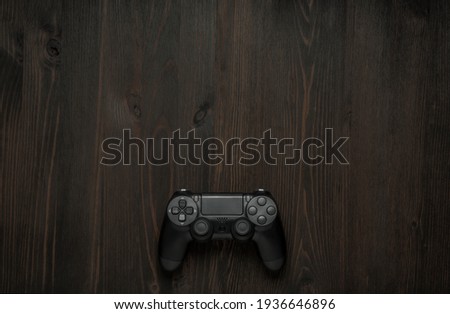 Modern black gamepad on a dark wooden background. Game concept with copy space for text.
