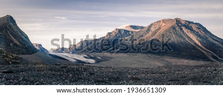 Sunset above above remote arctic valley of Akshayuk Pass, Baffin Island, Canada. Last rays of light on the peaks around Highway glacier. Arctic summer in the wild of the far north. Royalty-Free Stock Photo #1936651309