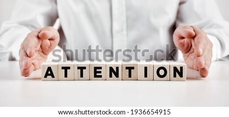 Businessman hands covers the wooden cubes with the word attention. Important announcement concept.

 Royalty-Free Stock Photo #1936654915