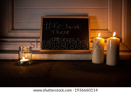 Chalk board with Reclaim the streets. Two large candles. One small tea light in a jar.