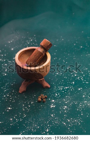 Handcrafted wooden mortar on a mystical dark background and a touch of pepper that gives a traditional style