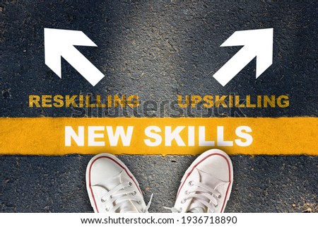 New skills development concept and changing skill demand idea. New skills written on yellow line with reskilling and upskilling with white arrow on asphalt road Royalty-Free Stock Photo #1936718890