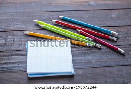 Pencils and notebook on wooden table