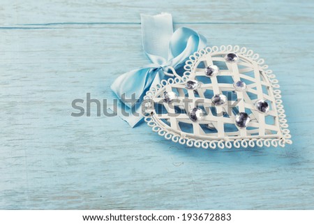 Decorative white heart on blue wooden background, horizontal. Selective focus.