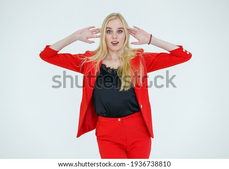 Indoor portrait of young cute blond hair woman in red clothes poses to camera in advertising gesture with cheerful and positive emotion isolated on white background.