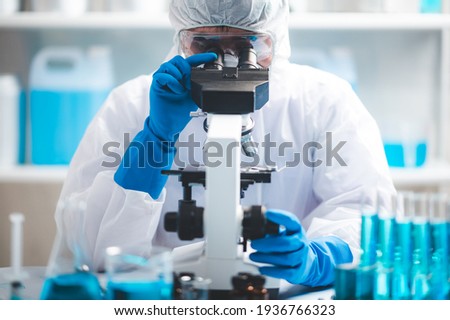 Scientist analyzing microscope slide at laboratory. Young woman technician is examining a histological sample, a biopsy in the laboratory of cancer research Royalty-Free Stock Photo #1936766323