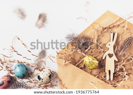 Easter eggs, hare, feathers, hay in a craft envelope on a white background. Holiday message happy Easter, correspondence concept. Flat lay, top view. Easter card.