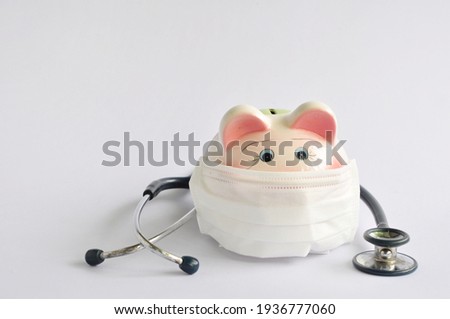 Piggy bank wearing a surgical mask and a stethoscope on a white background.