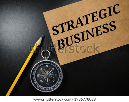 Business concept.Text STRATEGIC BUSINESS with compass and pencil on black background.