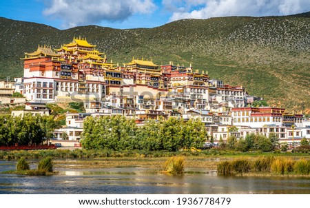 Scenic side view of Songzanlin monastery over mountain background on sunny day in Shangri-La Yunnan China Royalty-Free Stock Photo #1936778479