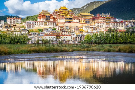 Songzanlin monastery with beautiful water reflection on lake in Shangri-La Yunnan China Royalty-Free Stock Photo #1936790620