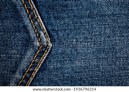 Background on the theme of denim clothing. Denim fabric with elements of seams.