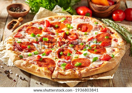 Pepperoni pizza with pizza sauce, mozzarella cheese and pepperoni. Pizza on wooden board on wood table with ingredients