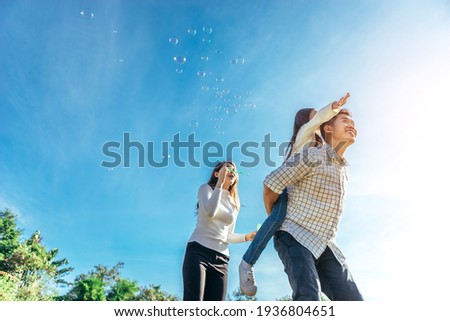 Happy asian family in the garden They are having fun playing and blowing bubbles. Royalty-Free Stock Photo #1936804651