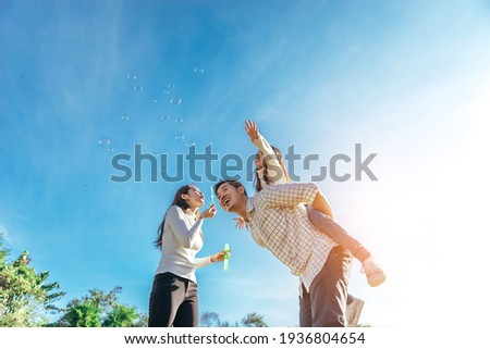 Happy asian family in the garden They are having fun playing and blowing bubbles. Royalty-Free Stock Photo #1936804654
